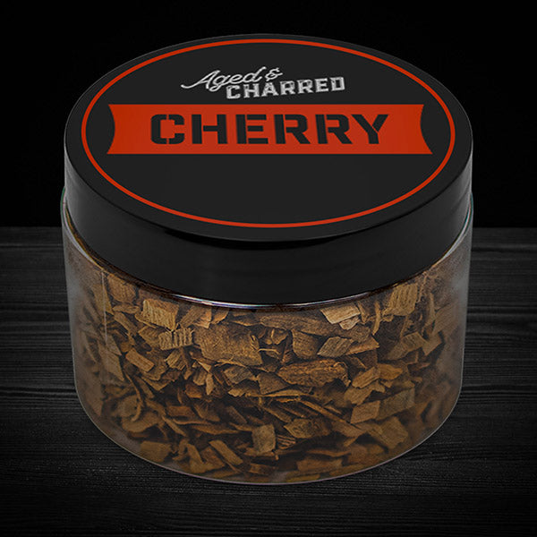 A clear container filled with cherry wood chips, with a black lid featuring the text 'AGED & CHARRED CHERRY'