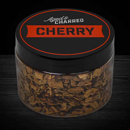 A clear container filled with cherry wood chips, with a black lid featuring the text 'AGED & CHARRED CHERRY'