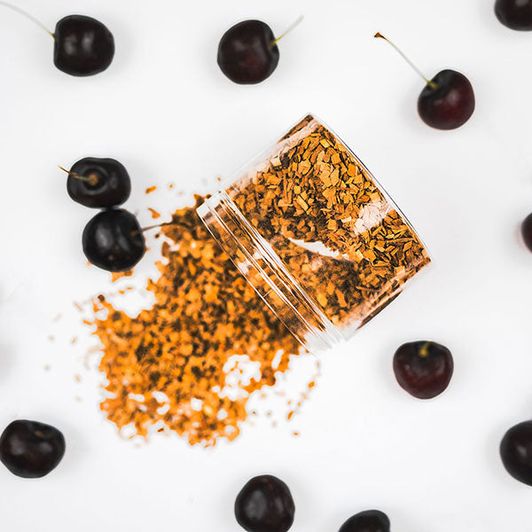 A clear container filled with cherry wood chips spilled