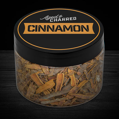 A clear container labeled 'Cinnamon' filled with wood chips, intended for whiskey infusion.