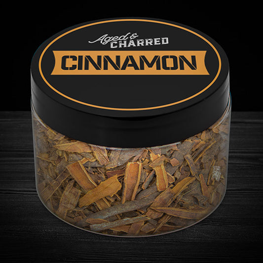 A clear container labeled 'Cinnamon' filled with wood chips, intended for whiskey infusion.