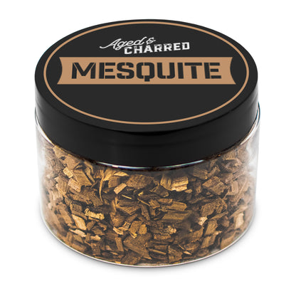 A clear container filled with mesquite wood chips, intended for whiskey infusion.