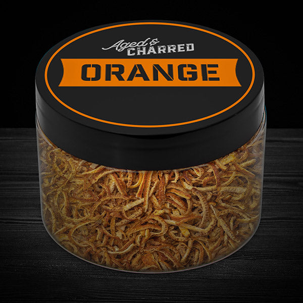 A clear container filled with aged and charred orange peel, with a black lid featuring the text 'AGED CHARRED ORANGE' on it.