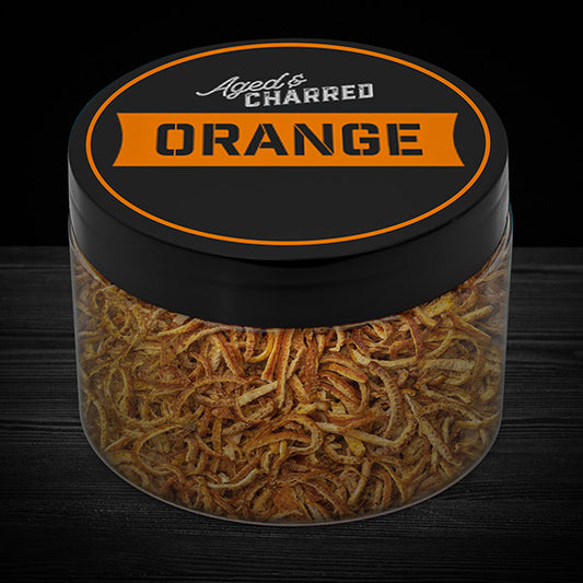 A clear container filled with aged and charred orange peel, with a black lid featuring the text 'AGED CHARRED ORANGE' on it.