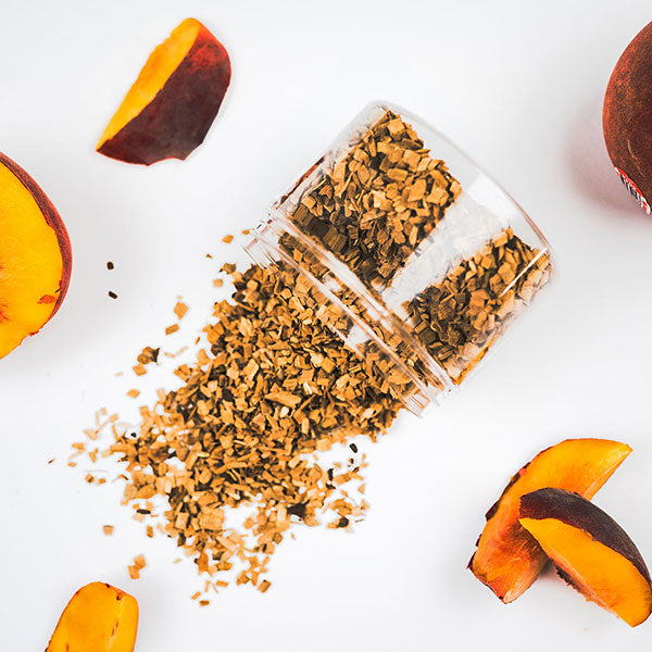 A clear container filled with peach wood chips spilled