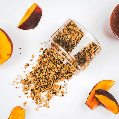 A clear container filled with peach wood chips spilled