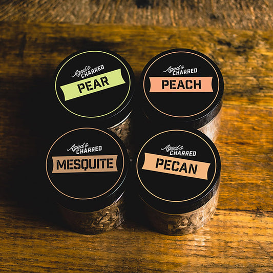 Four containers labeled peach, pear, mesquite, and pecan, containing wood chips for cocktail smoking.
