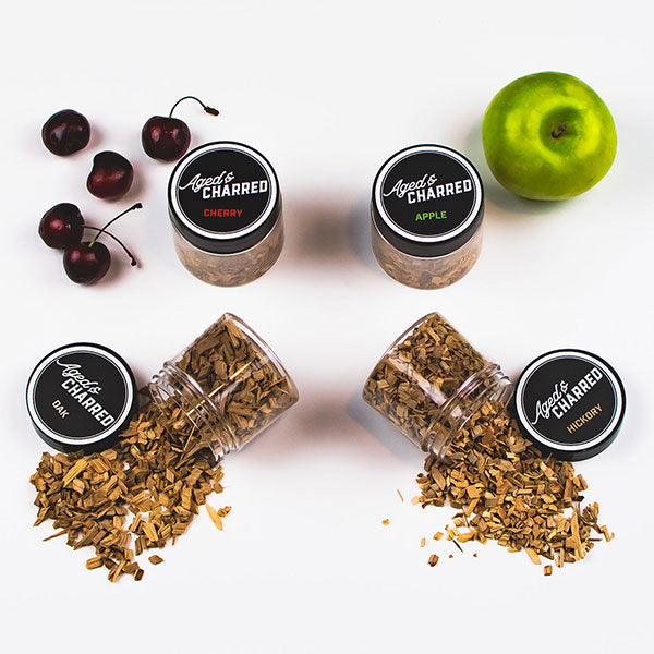 Four containers labeled Aged's Charred with different types of wood chips including Hickory, Apple, Cherry, and Oak